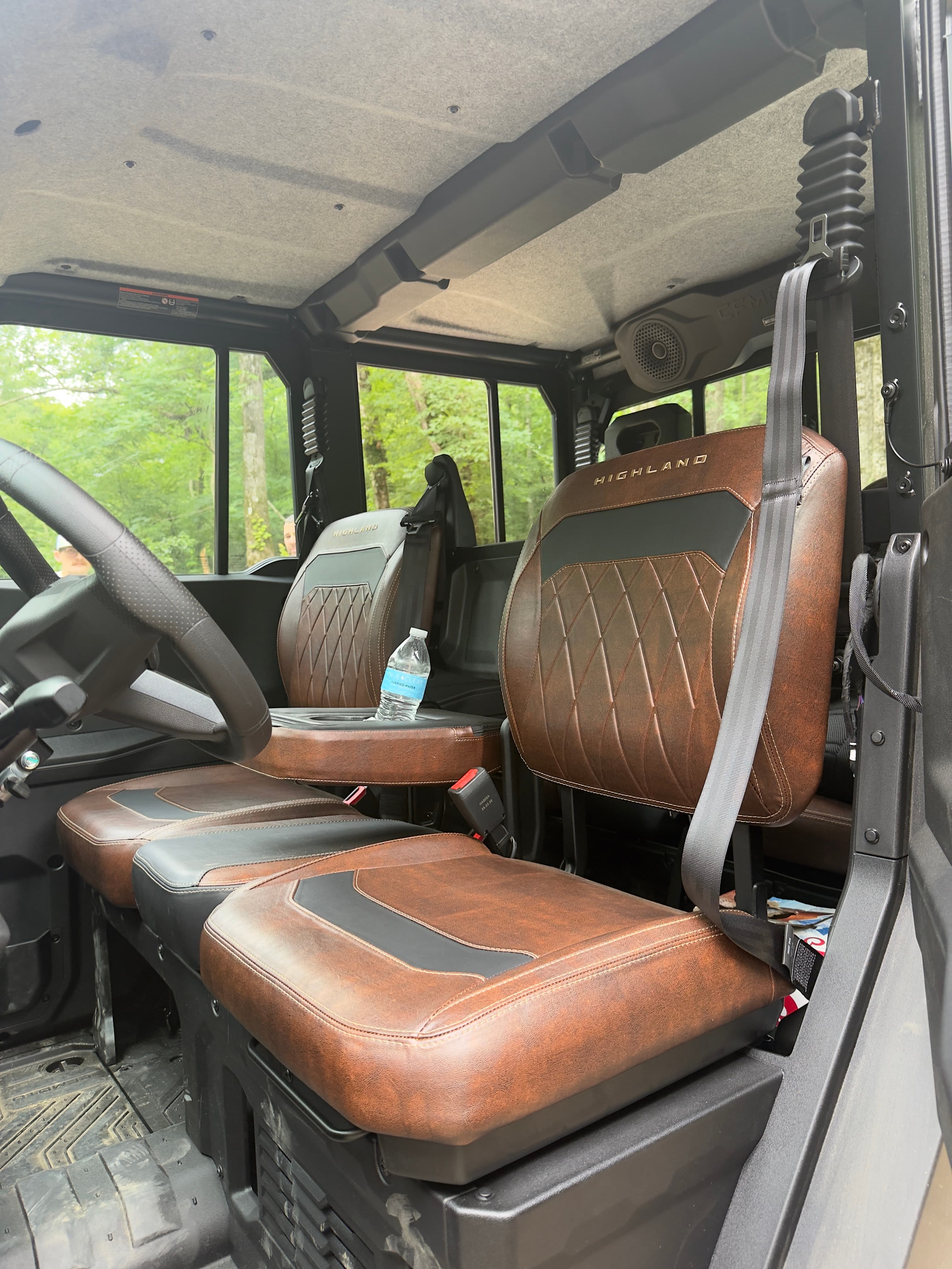Brown diamond-stitched seats and a black steering wheel inside a rugged Highland UTV cabin.
